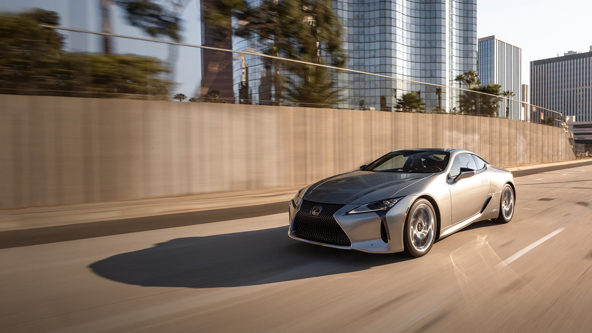 Silver Lexus LC being driven on the road in a city.