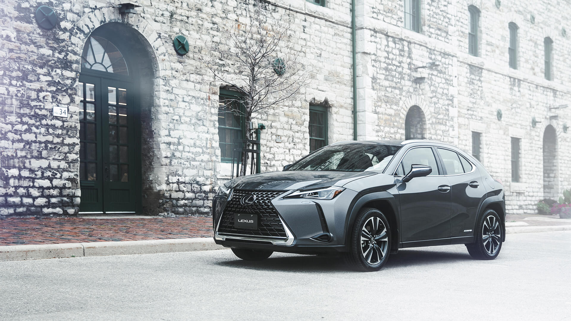 Grey Lexus UX in front of brick buildings.