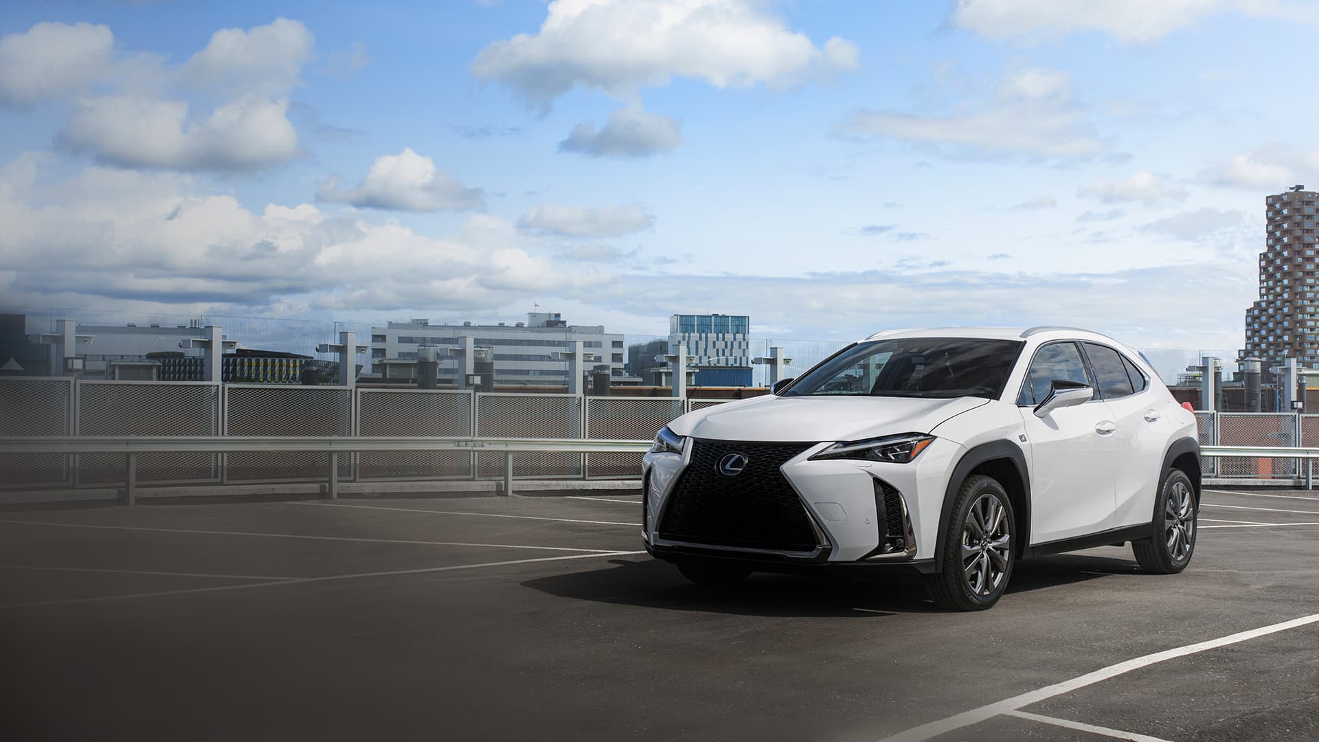 White Lexus UX on a rooftop carpark against a city backdrop.