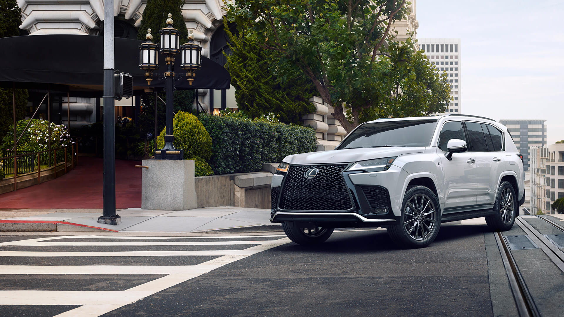 White Lexus LX being driven in a city.