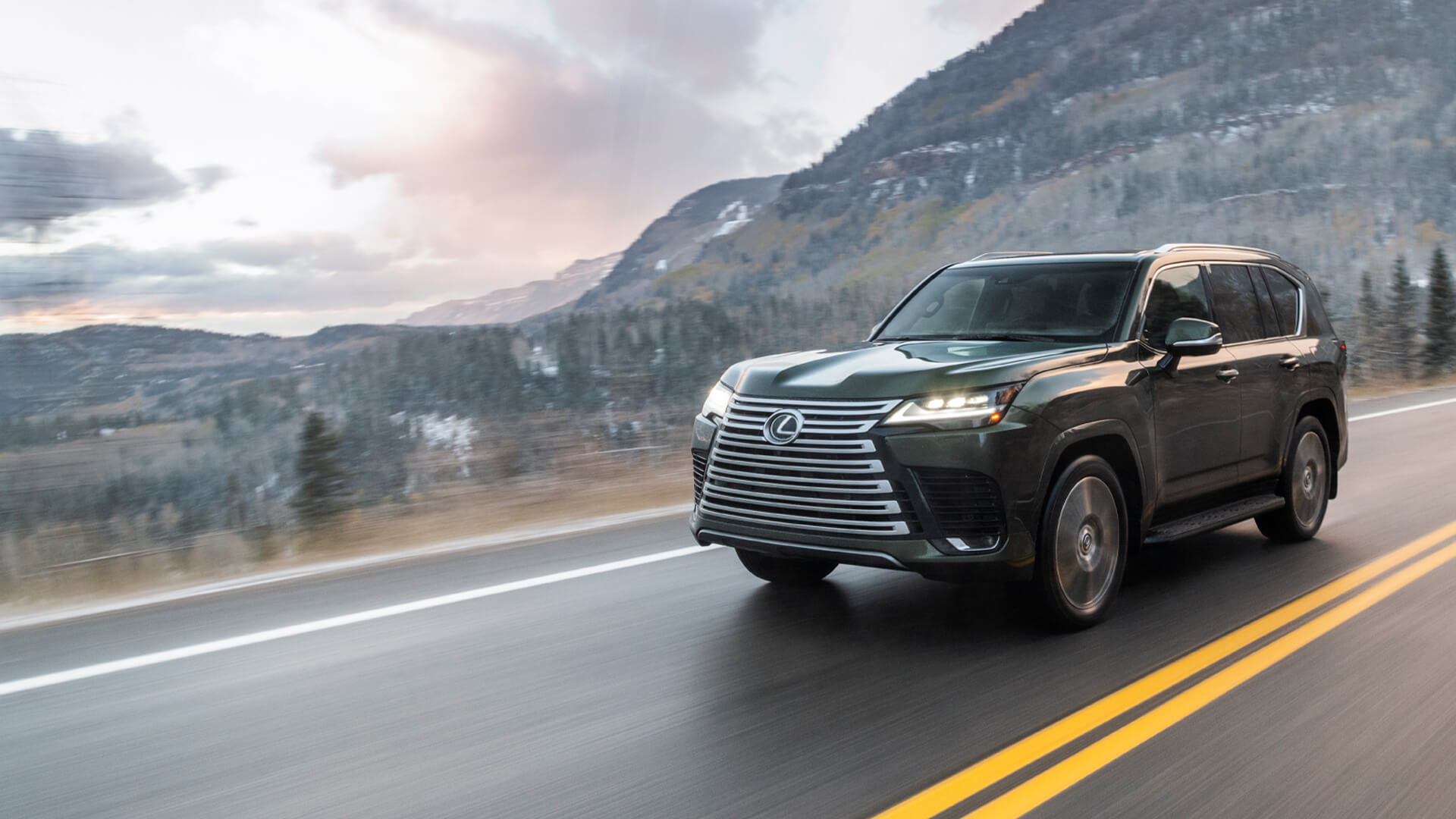 Lexus LX being driven on a road with mountains in the background.